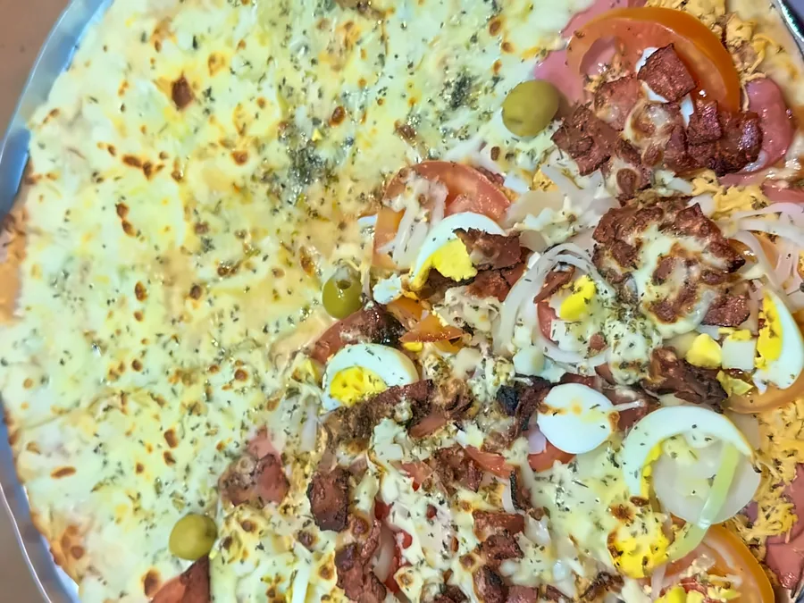 Pizza grande da Lussan, metade quatro queijos e metade portuguesa, na bandeja.